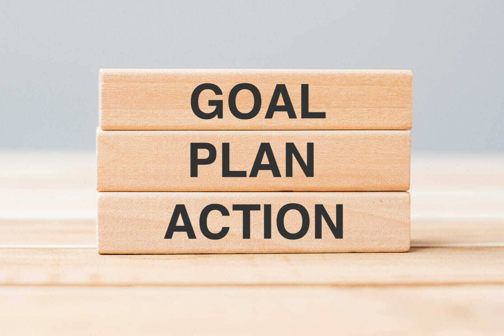 Wooden block with GOAL, PLAN and ACTION on table background